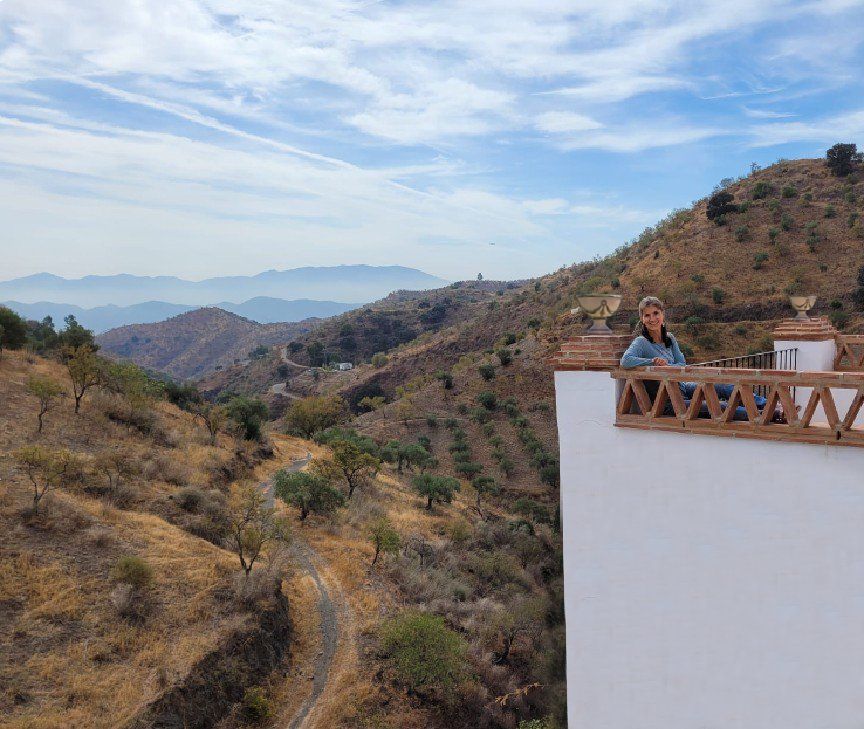 Carmen sentada en la terraza de la sala de las chimeneas, con preciosas vistas a las montañas.